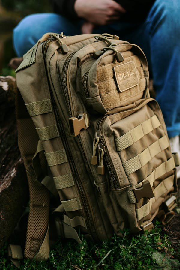Close-up of a khaki military backpack resting outside, perfect for travel or hiking.