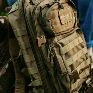 Close-up of a khaki military backpack resting outside, perfect for travel or hiking.